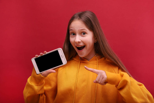 The happy girl shows her hand on the screen of an empty smartphone. - Fotoğraf, Görsel