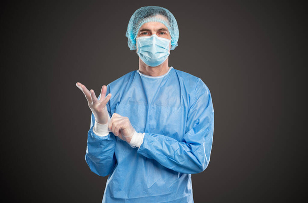 Male doctor putting on gloves before surgery - 写真・画像