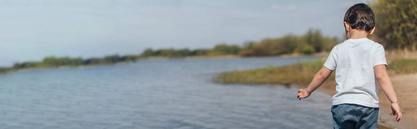 cabeçalho do site de menino de pé e gestos perto da lagoa
  - Foto, Imagem