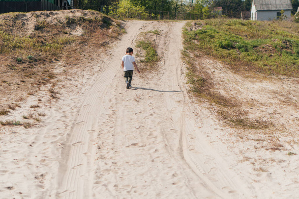 вид сзади ребенка, идущего по песку снаружи
 - Фото, изображение
