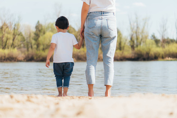 back view of mother and son standing near river - Photo, Image