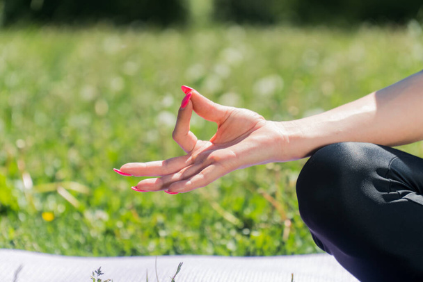 Close-up hands make a namaste during yoga. Young girl sits meditating on the mat - Φωτογραφία, εικόνα