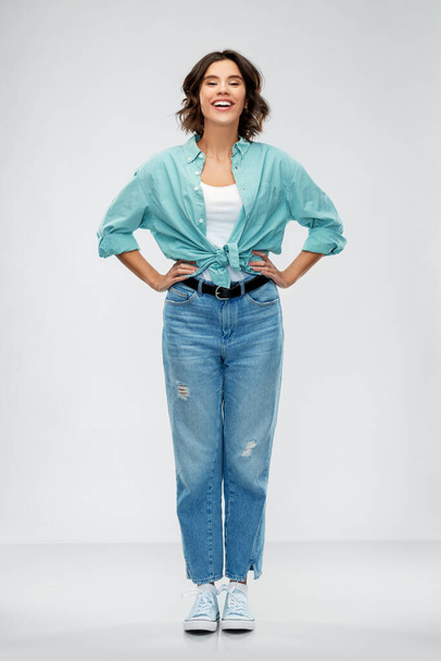 smiling young woman in turquoise shirt and jeans - Photo, image
