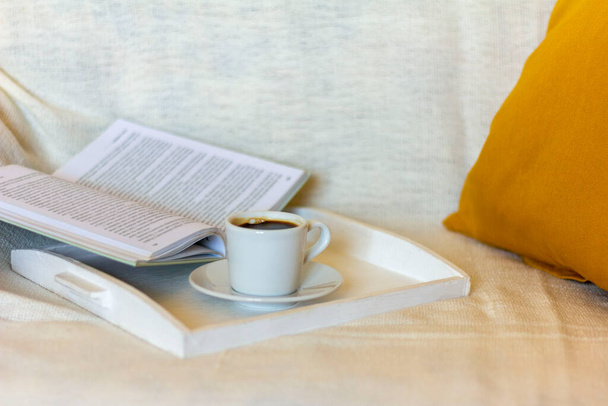 Pieni kuppi kahvia ja avoin kirja lämmintä huopaa.Käsite rentouttava viihtyisässä kotiympäristössä. - Valokuva, kuva