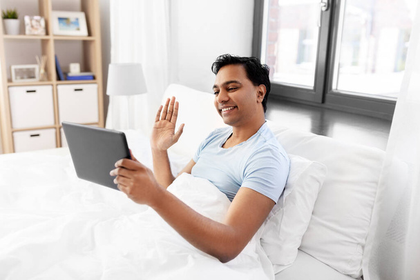 happy man with tablet pc in bed having video call - Foto, afbeelding