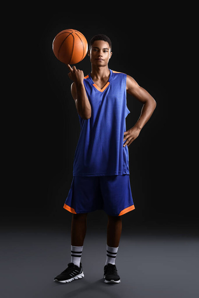 Joven jugador de baloncesto afroamericano sobre fondo oscuro
 - Foto, Imagen