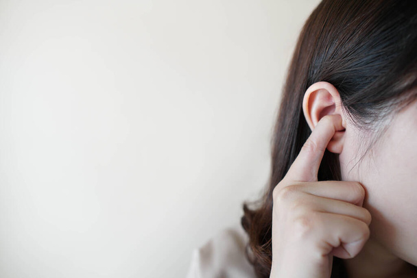 Young woman sticking plug fingers in ears and not listening to loud sound over white background w/ copy space. Loud noise can cause hearing loss, tinnitus or ear pain. Health and medical concept. - Photo, Image