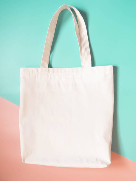 Mock up design bag concept. Blank white tote bag canvas fabric on orange green background. Empty eco bag. Copy space. Vertical. - Zdjęcie, obraz