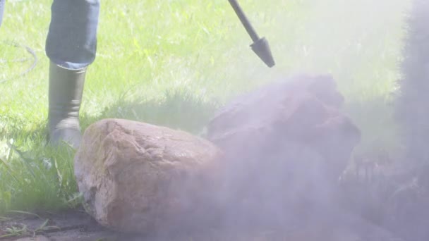 人は高圧洗浄機を使用して土から庭の石を洗う。晴れた日 - 映像、動画