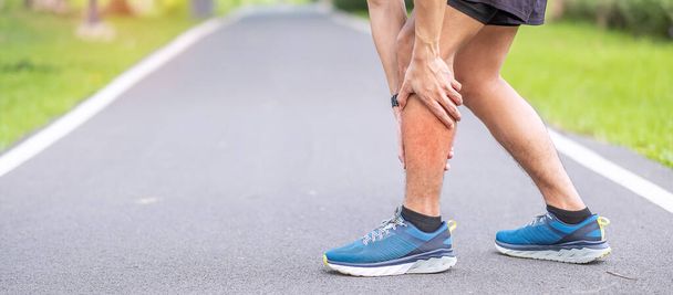 走っている間に彼の筋肉痛の若い大人の男性。カーフ・マッスル・プルのせいで足の痛みを持つランナーの男。スポーツ傷害と医療の概念 - 写真・画像