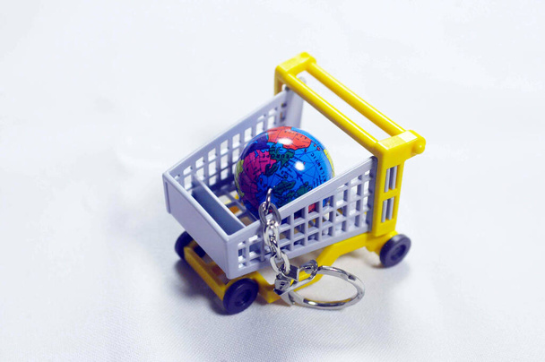 miniature shopping cart with globe in it, white background, world economy - Photo, Image
