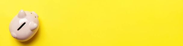 Egyszerűen minimális design rózsaszín malacka bank elszigetelt sárga háttérrel. Befektetési költségvetés megtakarítása vagyon üzleti nyugdíj pénzügyi pénz banki koncepció. Lapos feküdt felső nézet másolási hely banner - Fotó, kép