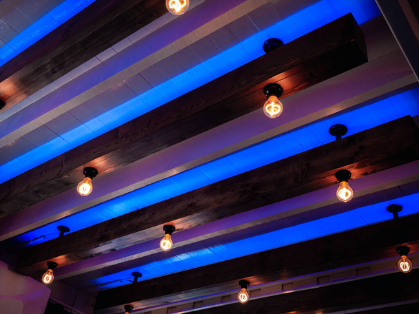 Décoration de plafond en bois dur et audacieux avec ampoules vintage. Plafond lumineux bleu et violet, style rétro. - Photo, image