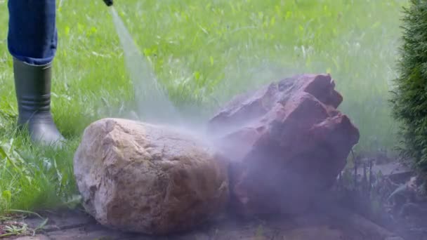 Zahradník myje dekorativní kameny ze špíny a mechu pomocí vysokotlaké podložky - Záběry, video