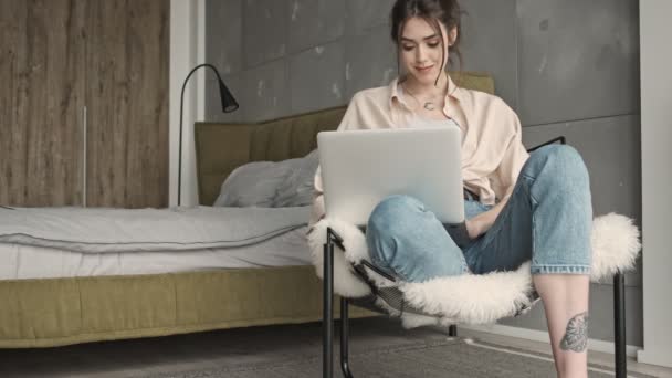 Junge positive Frau sitzt zu Hause und benutzt Laptop-Computer - Filmmaterial, Video