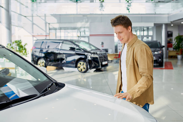 young male touches representative auto in cars showroom - Foto, Imagen