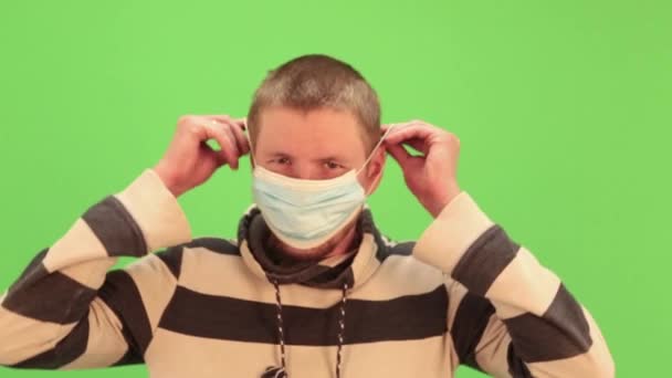 Man puts on medical mask on a chromakey. Virus protection gel, disinfectant. Prevent spread of coronavirus covid-19. - Záběry, video