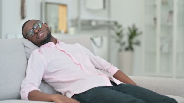Väsynyt nuori afrikkalainen mies ottaa nokoset sohvalla  - Materiaali, video