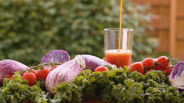 Cierre el jugo de tomate vertiendo en un vaso, verduras frescas sobre la mesa en gotas de agua. Cosechando en una granja de campo. Concepto de comida saludable
 - Foto, Imagen