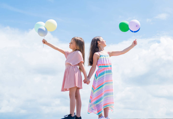 happy childhood. summer vacation. small girls embrace. love and support. concept of sisterhood and friendship. family bonding time. best friends with balloon. two sisters hold party balloon - Фото, изображение