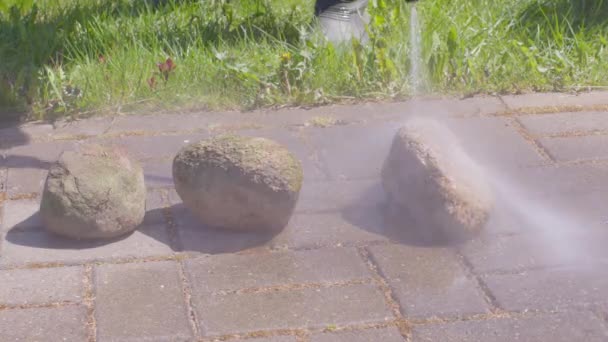 L'uomo lava pietre e lastre da pavimentazione da sporcizia utilizzando rondella ad alta pressione - Filmati, video
