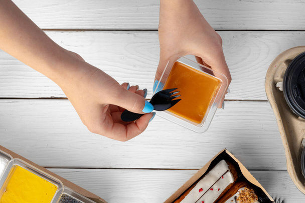 Female hands holding caramel dessert in a box above wooden table - Foto, immagini