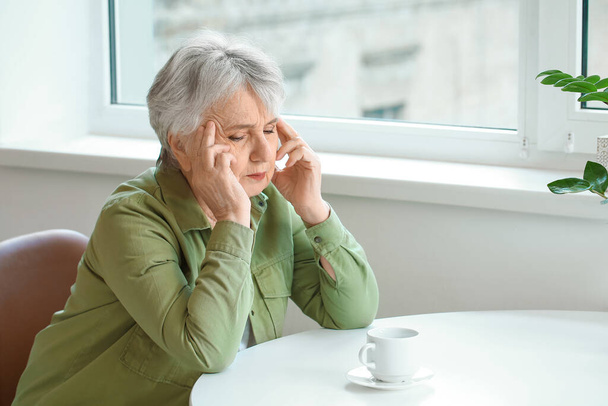 Seniorin leidet zu Hause unter Kopfschmerzen - Foto, Bild