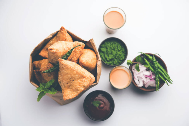 Samosa - ciasto w kształcie trójkąta, smażone / pieczone z pikantnym nadzieniem, popularne indyjskie przekąski Tea Time, podawane z zielonym chutney, ketchup pomidorowy - Zdjęcie, obraz