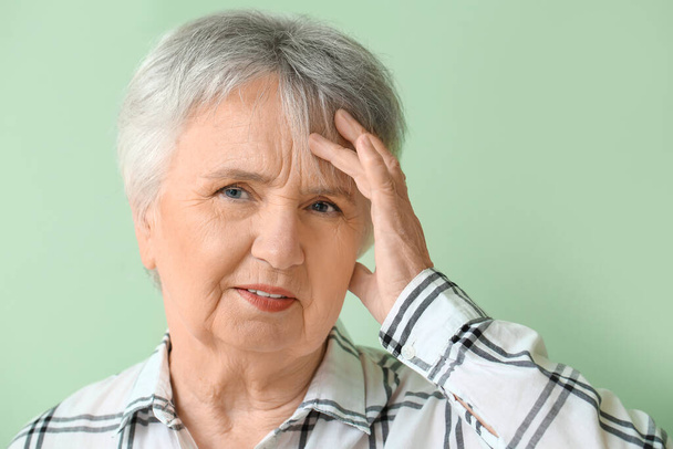 Senior woman suffering from headache on color background - Foto, Bild