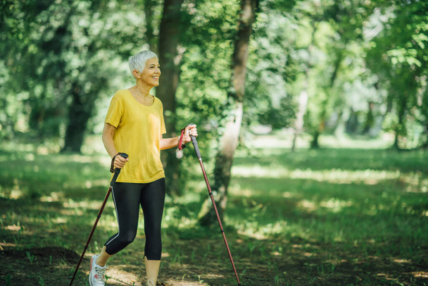Nordic walking exercise. Active mature woman enjoying the nature - 写真・画像