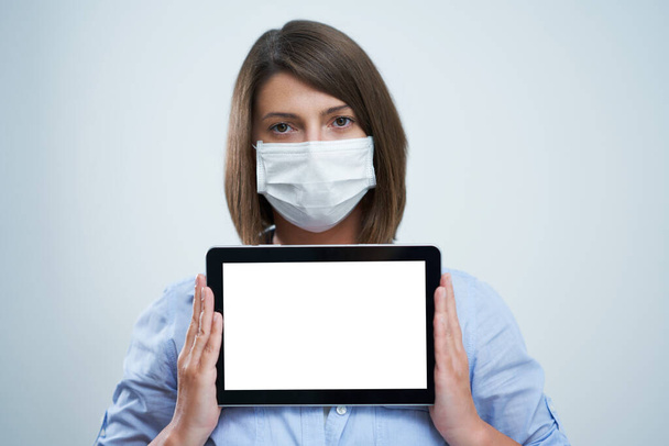 Woman wearing protective mask and holding tablet isolated over white background - Фото, зображення