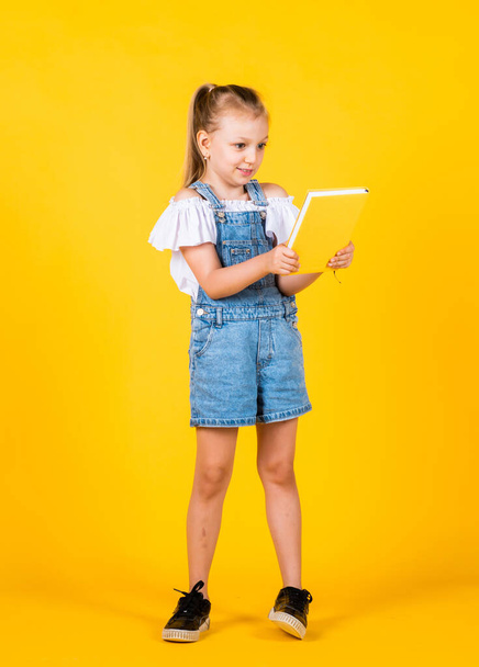 small girl hold notebook. read the book. ready for reading. lesson of literature. happy childhood. back to school. development of smart kids. express interest and intelligence - Foto, Imagen