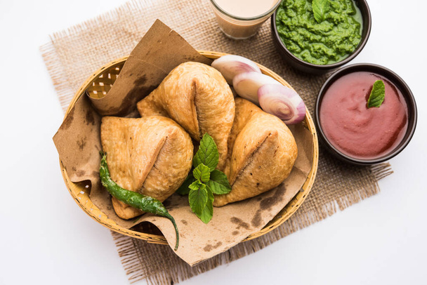 Samosa - Pastelería frita / horneada en forma de triángulo con relleno salado, populares aperitivos Indian Tea Time, servidos con chutney verde, ketchup de tomate
 - Foto, Imagen