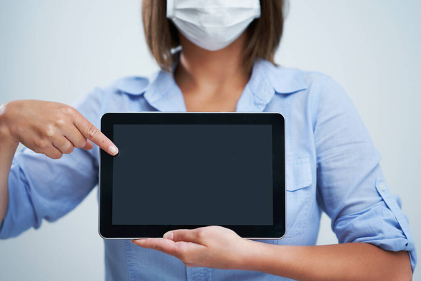 Woman wearing protective mask and holding tablet isolated over white background - Foto, imagen