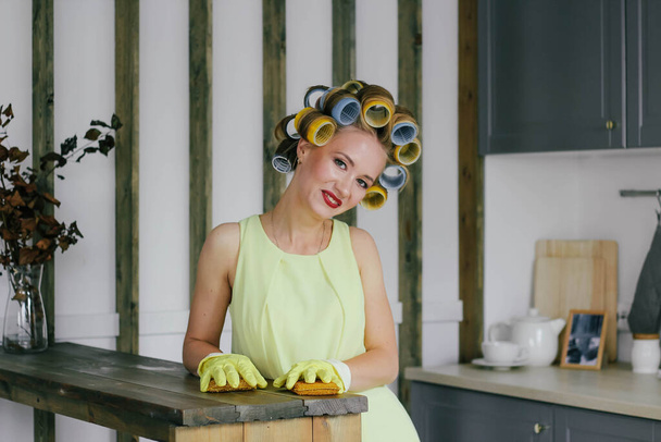 Tyttö blondi papiljotit ja keltainen mekko puhdistaa käsineet ja sieni - Valokuva, kuva