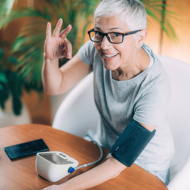 Vérnyomásmérőt használó idős nő - Fotó, kép