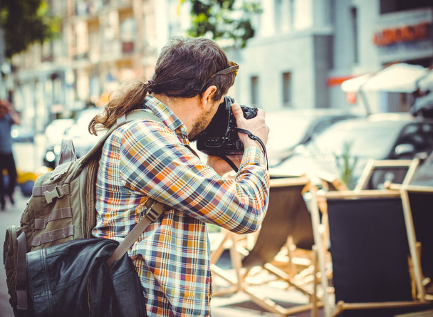 Um homem com uma câmera caminha pela cidade fotografando o bairro. O turista veio ver pontos turísticos europeus e dar um passeio com bom humor
 - Foto, Imagem