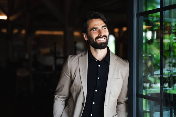 Portrait of businessman with jacket standing indoors in restaurant. - Foto, immagini