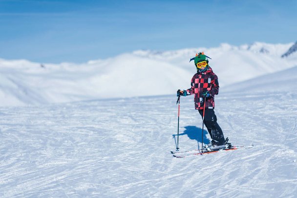 Νεαρό αρσενικό σκιέρ σε πολύχρωμο ντύσιμο στην κορυφή του χιονοδρομικού κέντρου βουνού. Αντιγραφή χώρου για κείμενο. - Φωτογραφία, εικόνα