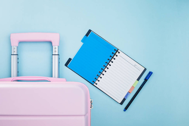 チェックリスト付きピンクの荷物旅行計画のコンセプトのための青の背景に日記 - 写真・画像
