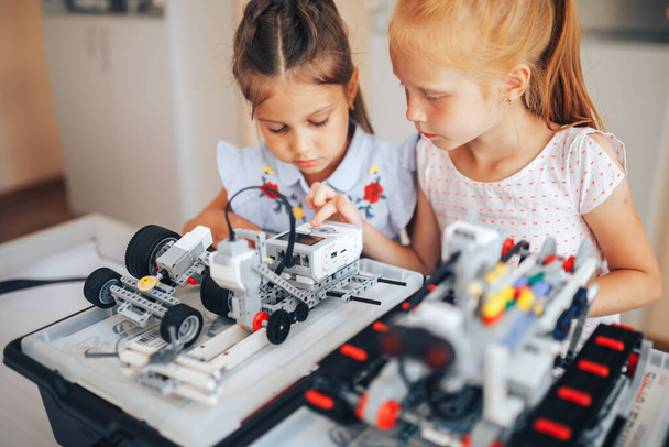 Two schoolgirls study in a robotics class, assemble a robot constructor. - Foto, immagini