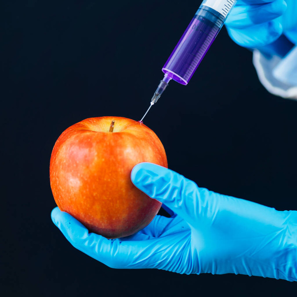 Espigar frutas con productos químicos para aumentar las ventas. Falta de práctica de inyectar productos químicos en la fruta de manzana
 - Foto, imagen