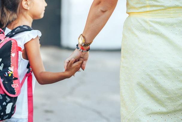 Мама держит за руку своего ребенка, мама сопровождает своего ребенка в школу, обратно в школу, день знаний - Фото, изображение