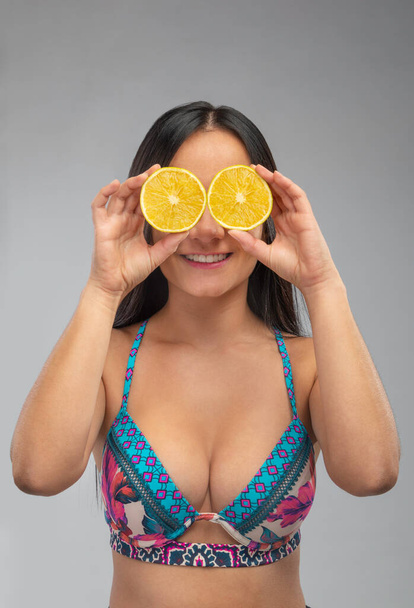 mujer latina sosteniendo dos naranjas en sus ojos sonriendo y jugando
  - Foto, imagen