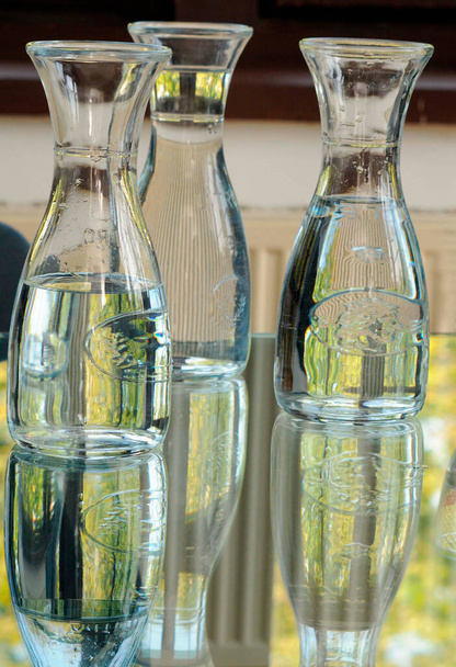 three bottles differently filled with water standing on a glass table - Photo, image