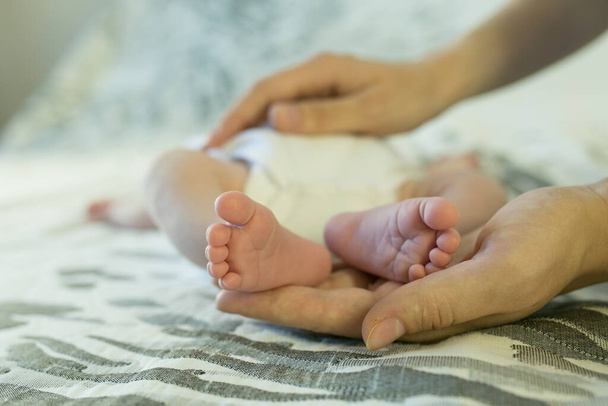 Çocuklar işte. Bebekler. Çocuk bakımı. Yeni doğmuş bir bebeğin küçük bacakları mutlu ebeveynlerin ellerinde. - Fotoğraf, Görsel