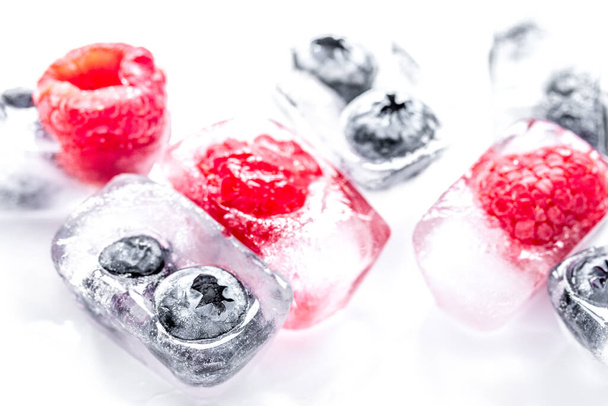 Ice cubes with frozen berries on white background - Fotó, kép