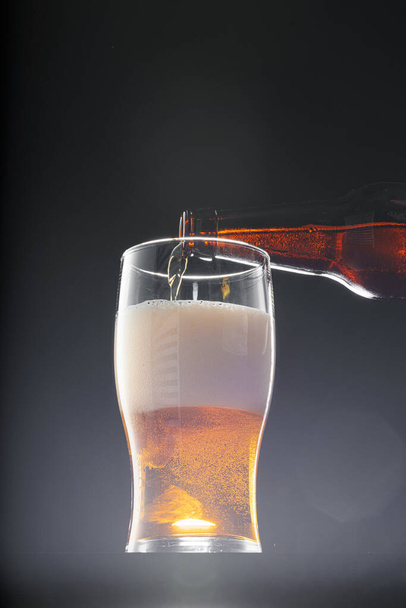 Beer pouring into glass on black background - Fotoğraf, Görsel
