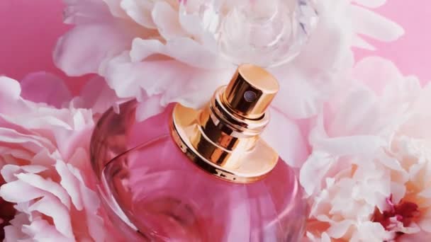 Pink parfém láhev s pivoňkami květiny, elegantní vůně jako luxusní kosmetické, módní a kosmetické pozadí - Záběry, video