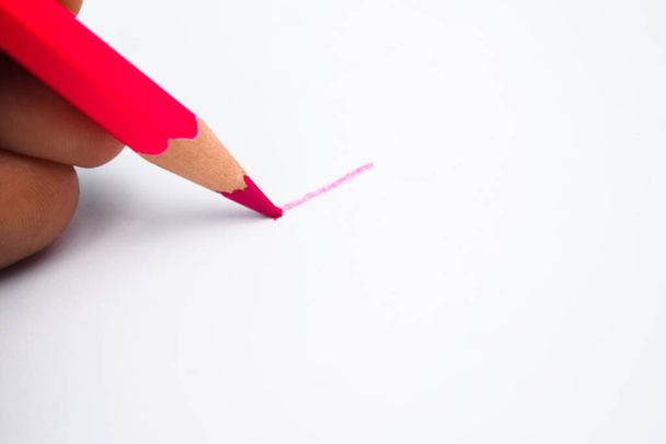 Henkilö piirtää viivan terävällä punaisella lyijykynällä värikynällä puhtaalle valkoiselle paperille - Valokuva, kuva